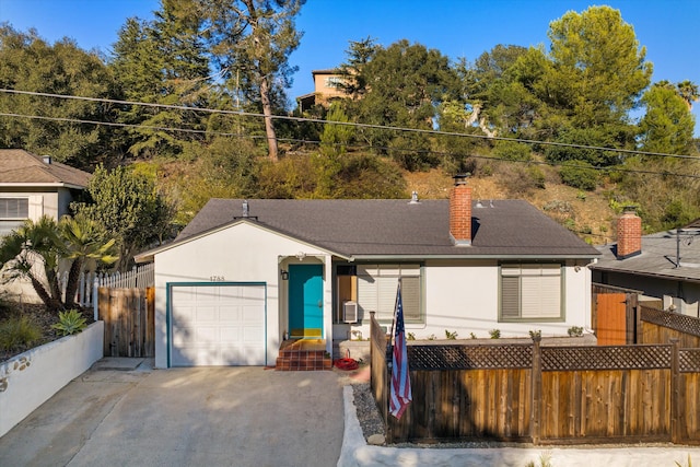 ranch-style house with a fenced front yard, a chimney, stucco siding, concrete driveway, and an attached garage