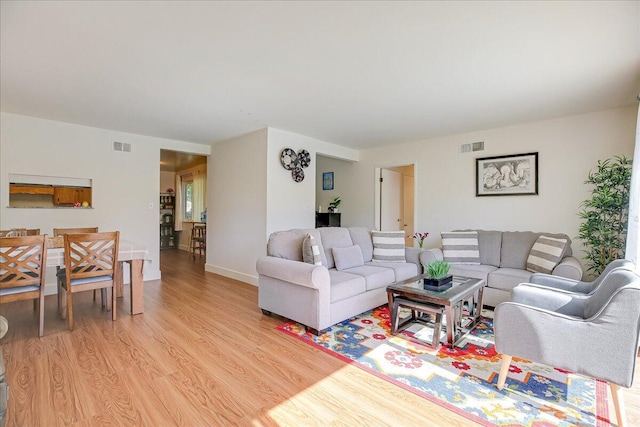 living area featuring light wood-style flooring, visible vents, and baseboards