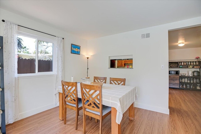 dining room with light wood-style flooring, visible vents, and baseboards