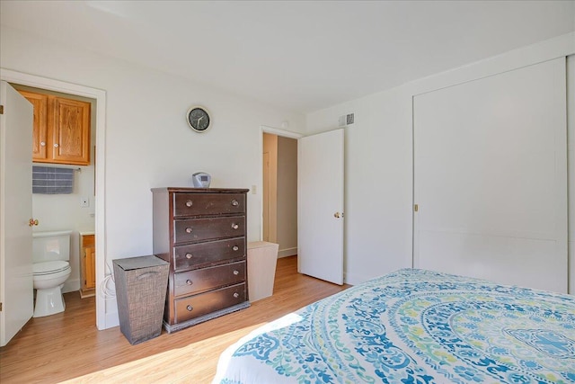 bedroom featuring light wood-type flooring, visible vents, and ensuite bathroom