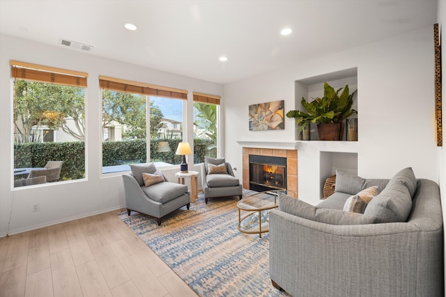 living room featuring recessed lighting, a fireplace, wood finished floors, visible vents, and baseboards