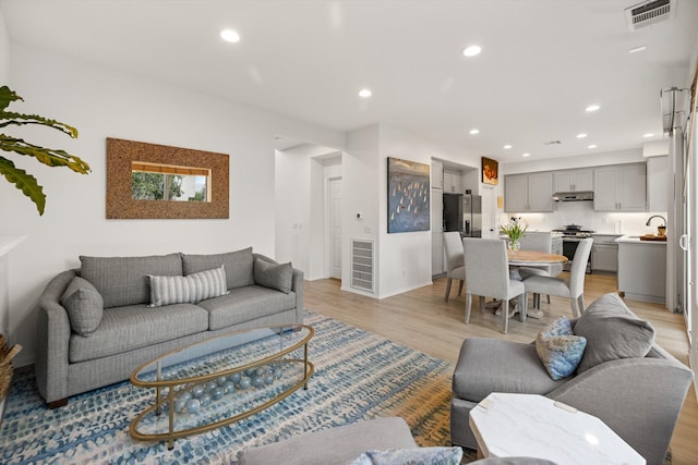 living area with recessed lighting, visible vents, and light wood-style floors