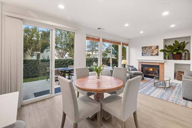 dining area with light wood-style flooring, a fireplace, and a wealth of natural light