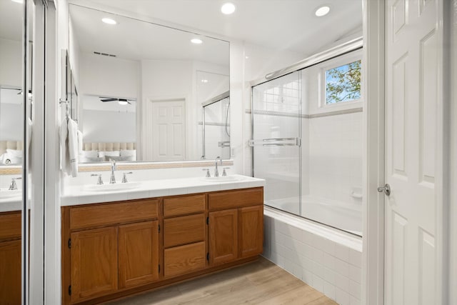 ensuite bathroom with double vanity, tiled shower / bath combo, a sink, and visible vents