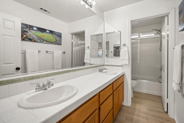 full bathroom featuring toilet, double vanity, a sink, and visible vents