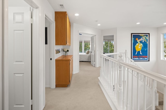 hallway featuring recessed lighting, visible vents, light carpet, and an upstairs landing