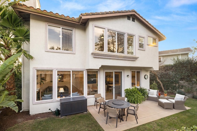 back of property with outdoor lounge area, a patio area, a tile roof, and stucco siding