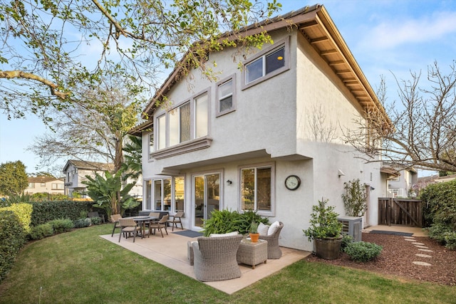 back of house featuring a lawn, a patio area, fence, and stucco siding