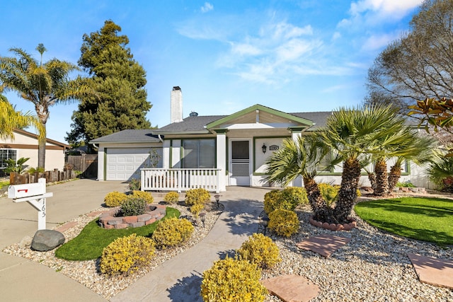 view of front facade with driveway, a chimney, an attached garage, fence, and stucco siding