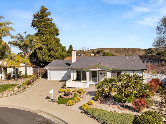 ranch-style home featuring concrete driveway, fence, a chimney, and an attached garage