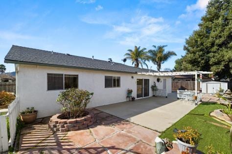 back of property featuring a patio area, fence, an outbuilding, and stucco siding