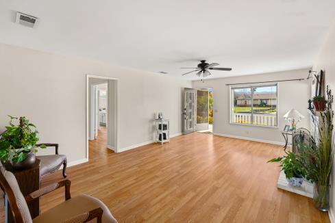 living room featuring baseboards, ceiling fan, visible vents, and light wood-style floors