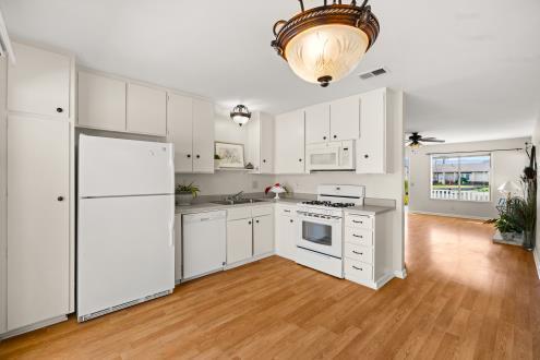 kitchen with light wood-type flooring, white appliances, visible vents, and a sink