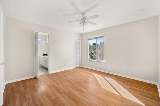 unfurnished bedroom featuring a closet, light wood-style flooring, a ceiling fan, connected bathroom, and baseboards