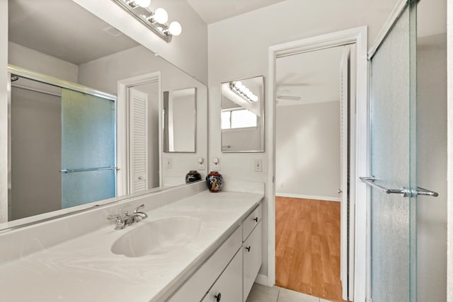 full bathroom with an enclosed shower, vanity, baseboards, and wood finished floors