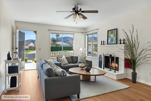 living room featuring a brick fireplace, ceiling fan, baseboards, and wood finished floors