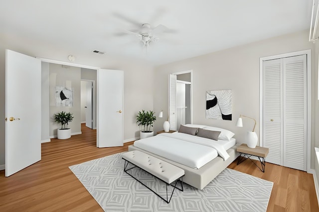 bedroom with light wood finished floors, a ceiling fan, visible vents, and baseboards