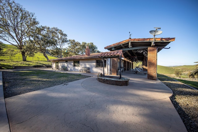 back of house featuring a tile roof, a chimney, stucco siding, a patio area, and fence