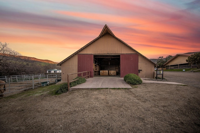 view of outdoor structure featuring an outbuilding, driveway, fence, and a mountain view