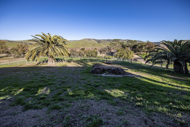 exterior space with a rural view, fence, and a mountain view