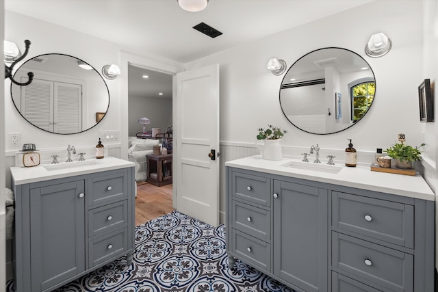 ensuite bathroom with a wainscoted wall, two vanities, a sink, and ensuite bathroom