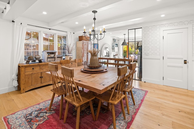 dining room with light wood-type flooring, wainscoting, beam ceiling, wallpapered walls, and an inviting chandelier