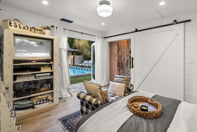 bedroom featuring access to exterior, recessed lighting, light wood-style floors, and a barn door