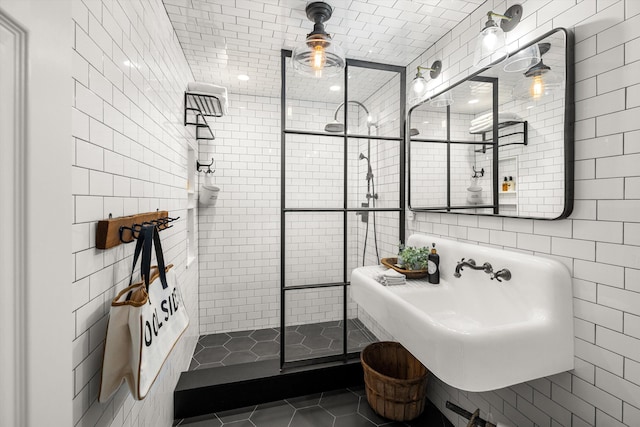 bathroom featuring a sink, tile patterned flooring, walk in shower, and tile walls