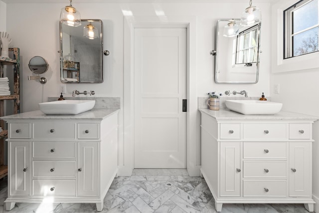 bathroom with marble finish floor, two vanities, and a sink