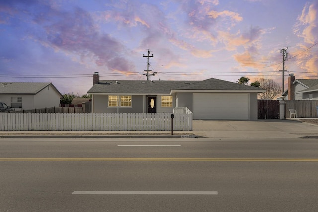 single story home featuring driveway, a fenced front yard, an attached garage, and stucco siding