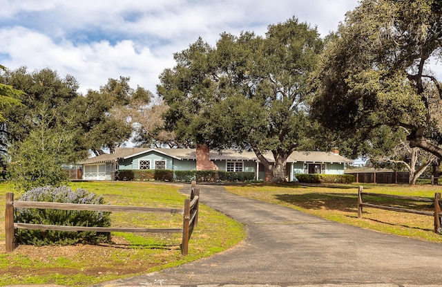 single story home featuring driveway, a fenced front yard, and a front lawn