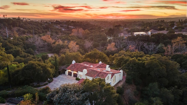 aerial view at dusk featuring a wooded view