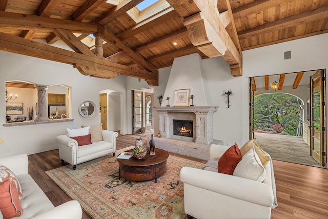 living area with vaulted ceiling with skylight, wood ceiling, a fireplace, and arched walkways