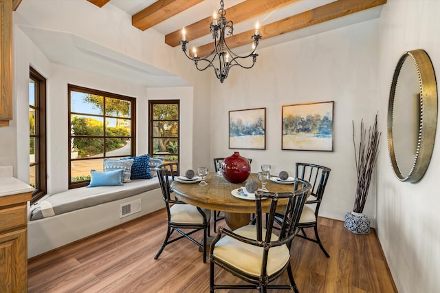 dining room with an inviting chandelier, beam ceiling, visible vents, and wood finished floors