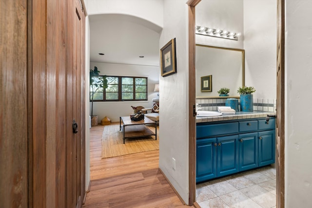 interior space with arched walkways, a sink, and light wood-style flooring