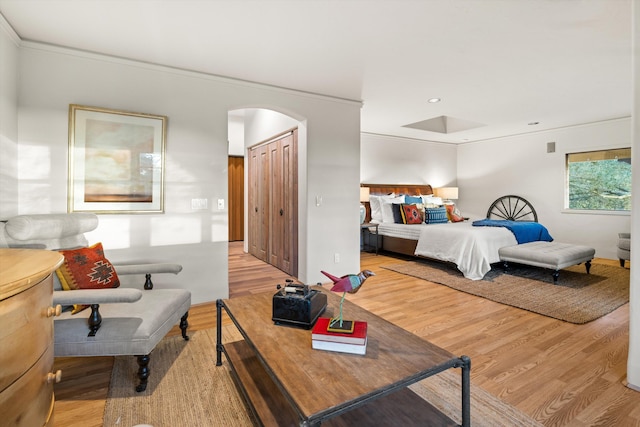 bedroom with light wood-type flooring, arched walkways, ornamental molding, and recessed lighting