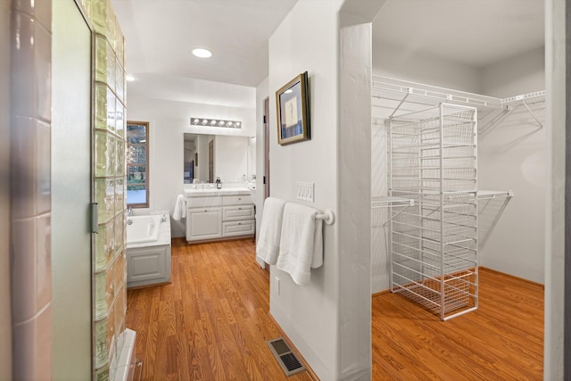 full bathroom featuring a bath, visible vents, wood finished floors, and vanity