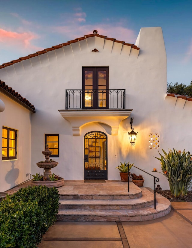 doorway to property with french doors, a balcony, and stucco siding