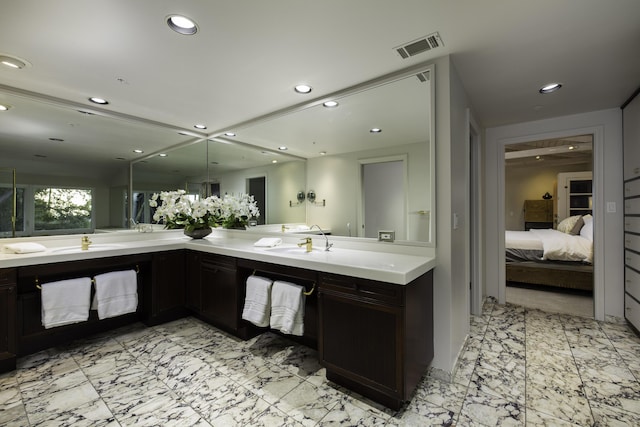 ensuite bathroom featuring a sink, marble finish floor, connected bathroom, and recessed lighting