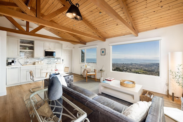 living area with lofted ceiling with beams, light wood finished floors, wood ceiling, and baseboards