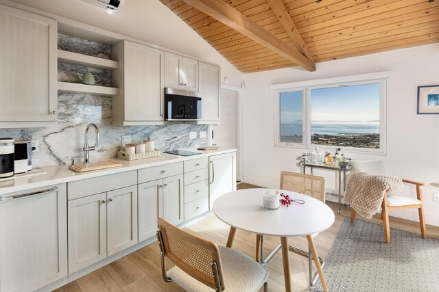 kitchen featuring stainless steel microwave, vaulted ceiling with beams, light countertops, open shelves, and a sink