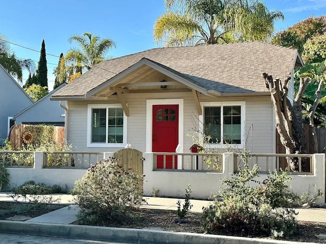 bungalow-style home with a fenced front yard, a gate, and roof with shingles