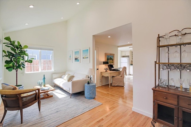 living room with high vaulted ceiling, light wood-style flooring, and recessed lighting