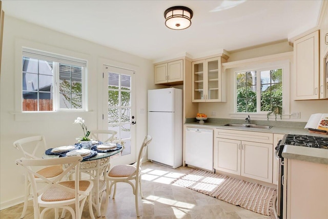 kitchen featuring light countertops, white appliances, a sink, and glass insert cabinets