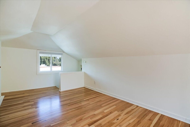 additional living space with light wood finished floors and vaulted ceiling