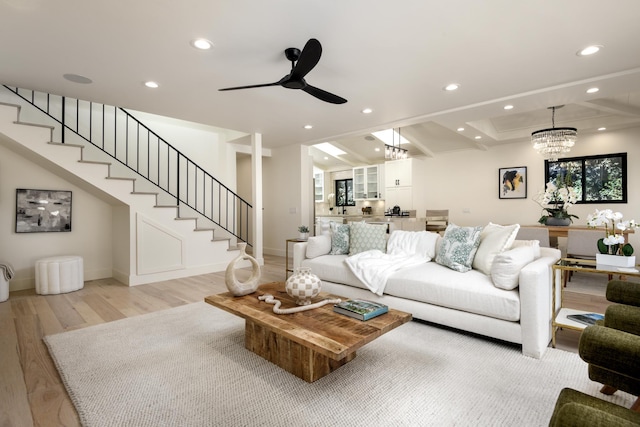 living area featuring light wood finished floors, baseboards, stairway, recessed lighting, and ceiling fan with notable chandelier