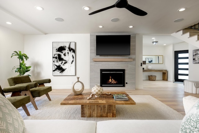 living room featuring recessed lighting, a large fireplace, and wood finished floors