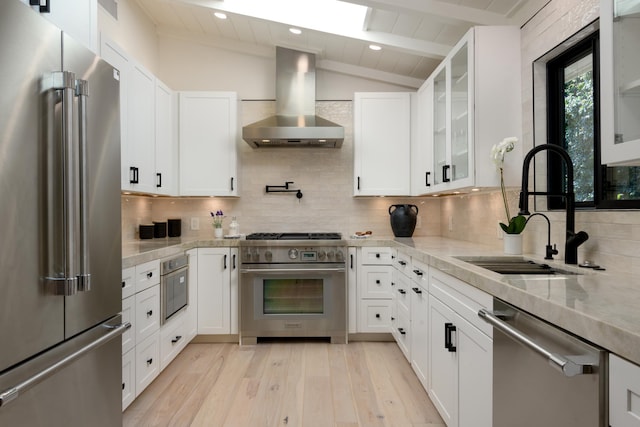 kitchen with vaulted ceiling with beams, premium appliances, a sink, wall chimney range hood, and tasteful backsplash