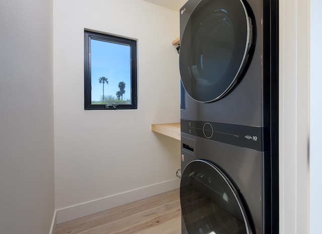 laundry room with laundry area, baseboards, stacked washer / drying machine, and light wood-type flooring