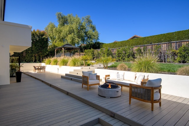 wooden deck featuring an outdoor living space with a fire pit, a gazebo, and fence